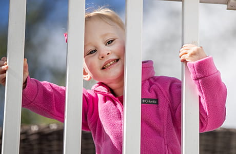 Kinlee Hock looking through a fence.