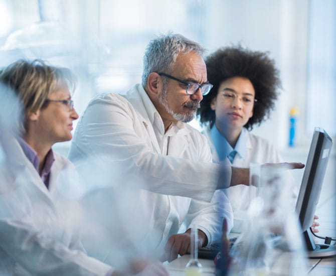 an image of three people looking at a computer monitor