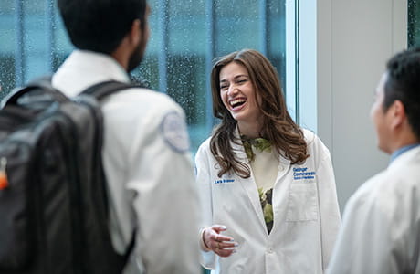 Three medical students laughing and talking in a hallway