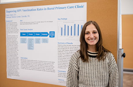 A woman standing in front of a chart smiling