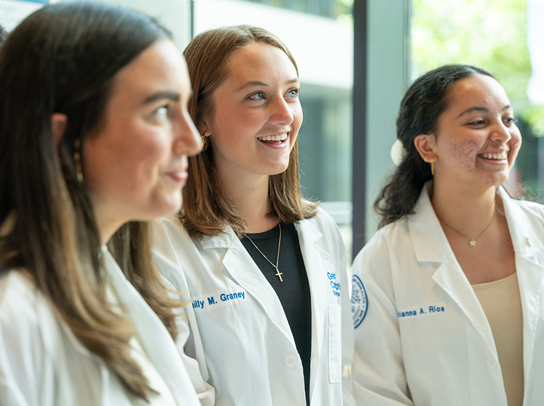 Three female students stand outside smiling