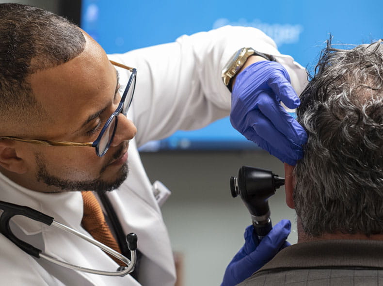 A doctor looking into a mans ear.