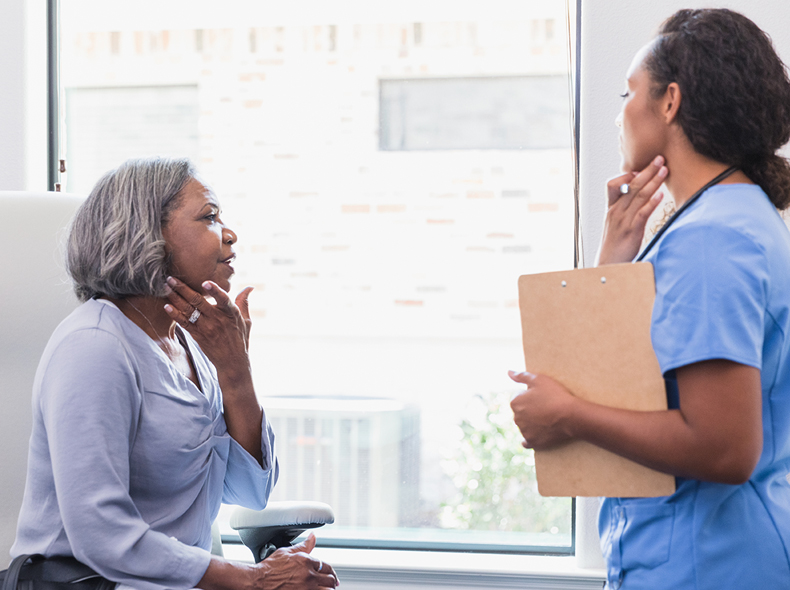 Woman talking to doctor touching her neck. 