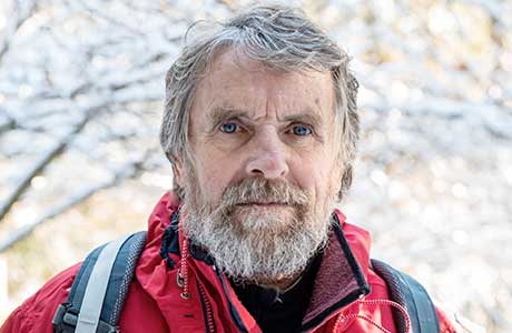 an elderly man standing in an orchard