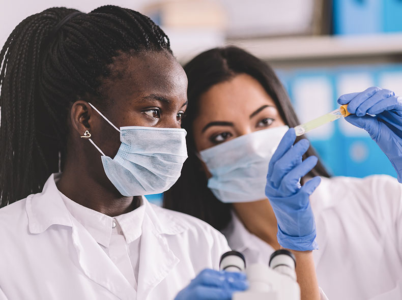 Two woman looking at contents in a vial.