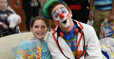 Little Ava seated with clown at Janet Weis Children’s Hospital
