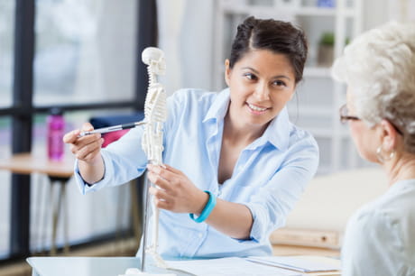 Doctor reviewing a skeleton with an older woman.