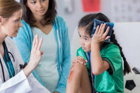 Girl holds ice pack to head while being examined for a concussion