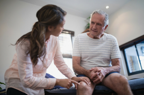 Physical therapist touches a men's knee
