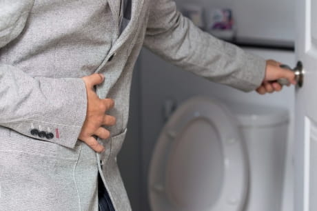 Man holding stomach going into bathroom