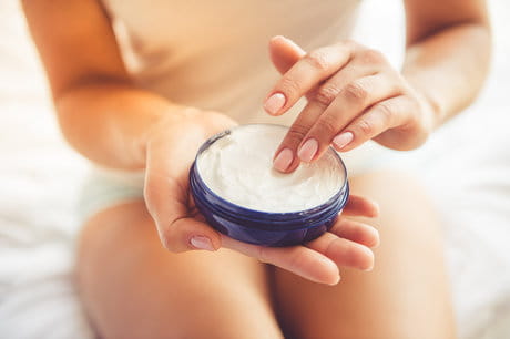 Woman applies cream to help soothe her dry winter skin.
