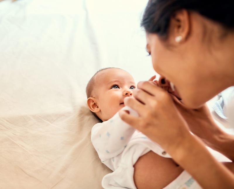 New mom cuddling smiling newborn baby.