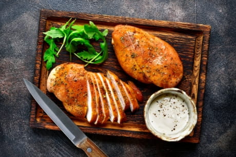 Sliced, lightly pan-fried chicken on a cutting board.