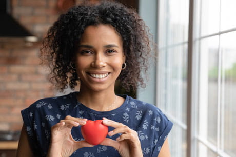 Woman holding a heart shape to bring awareness to heart attack symptoms in women