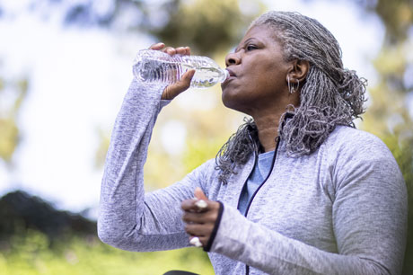 A woman drinking an 8 ounce bottle of water.