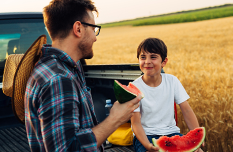A man and boy eating watermelon. 