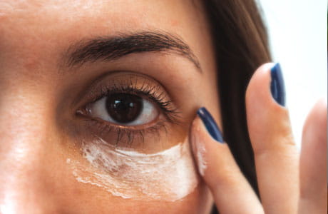 Woman putting on eye cream. 