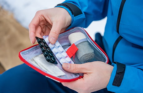 First aid kit containing pills, bandages, and other medical supplies.