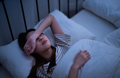 A woman laying in bed with a headache