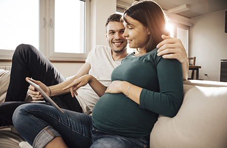 Happy pregnant couple viewing computer together. 