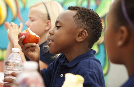 School kids eating an apple and drinking water. 