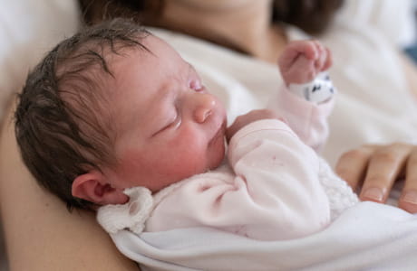 New born baby resting in moms arms. 