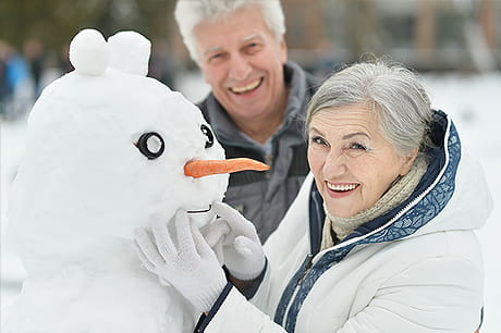 Older couple bundled up on a snowy day outside