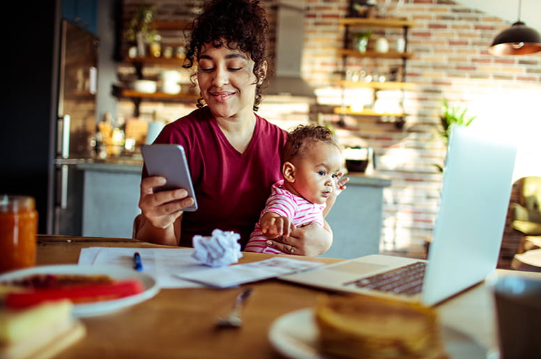 Mom holding baby at a table looking at her phone using the MyGeisinger Patient Portal