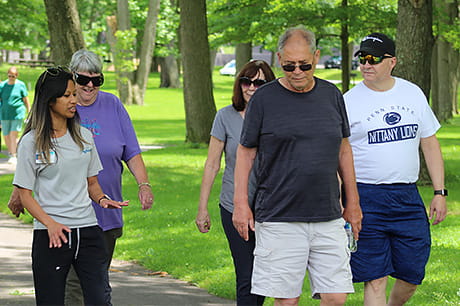 A small group of people engage in conversation while walking in a park.
