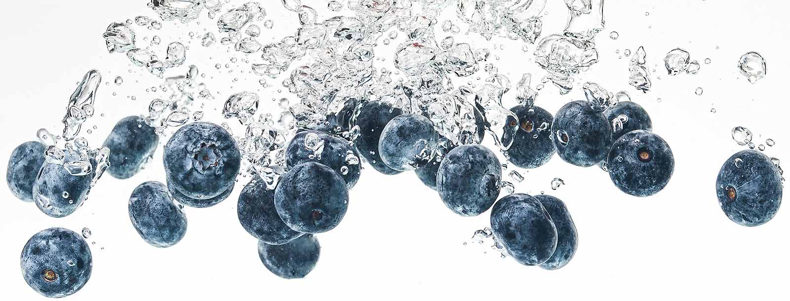 Several blueberries make a splash into water.