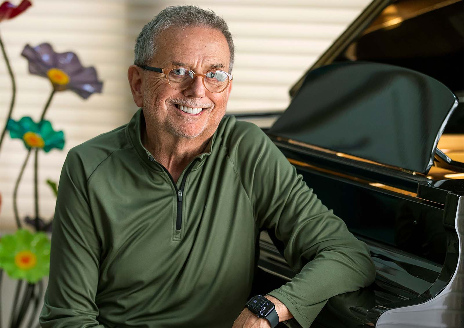 Physician Charlie White seated at the bench of his piano.