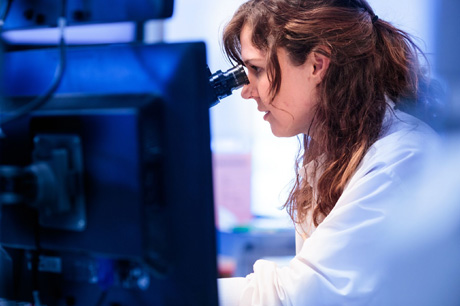 A woman looking into a microscope